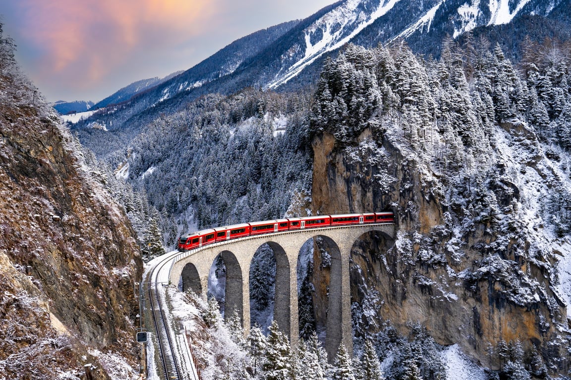 Train passing through snow-capped mountains in Filisur, Switzerland